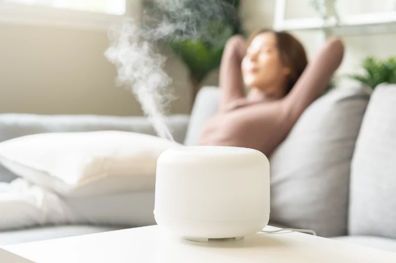 A woman relaxing on a couch with an aroma diffuser.