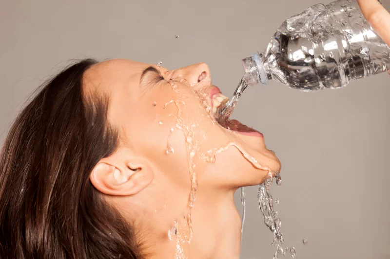 A woman drinking water from a bottle.