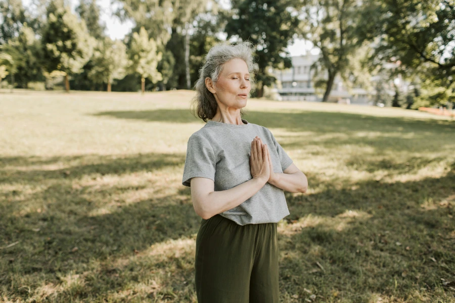  A woman practicing breathing through mouth while meditating in the park. 