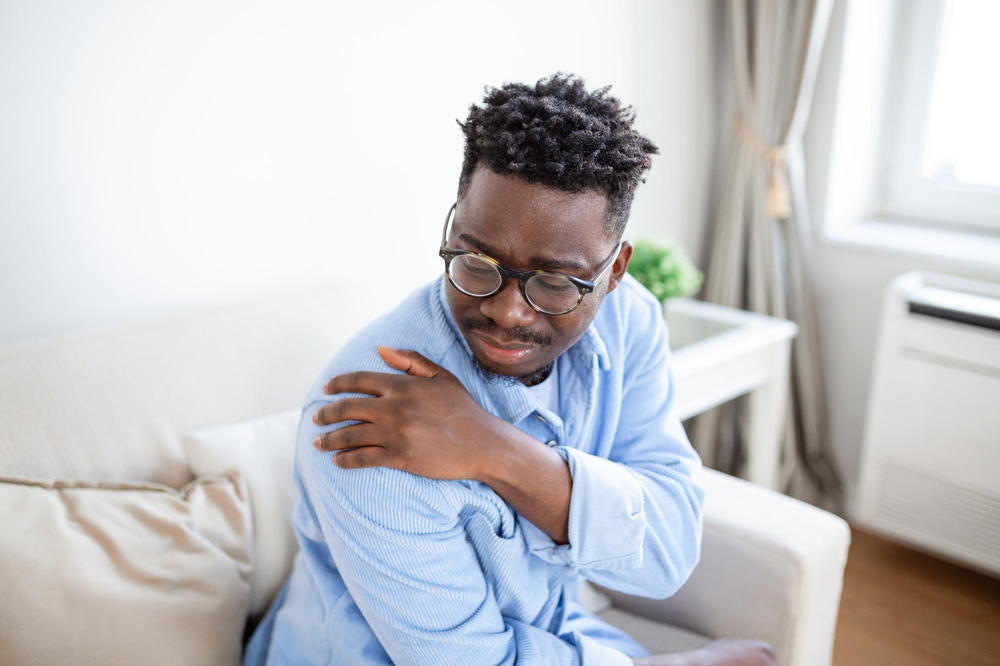 A man experiencing shoulder pain and considering using Medical Marijuana products to reduce that pain.