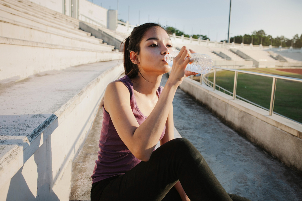 A woman drinking water to soothe the cotton mouth she is experiencing after using Medical Marijuana. 