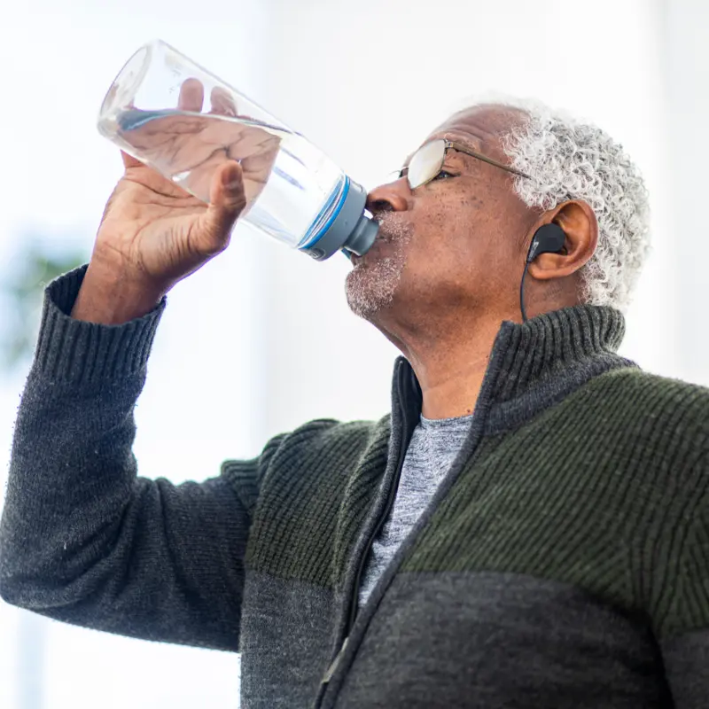  A man with cottonmouth drinking water to alleviate his dry mouth.