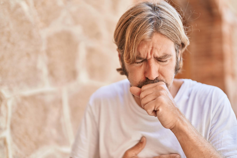 A man has a sore throat and is coughing because of his cottonmouth.